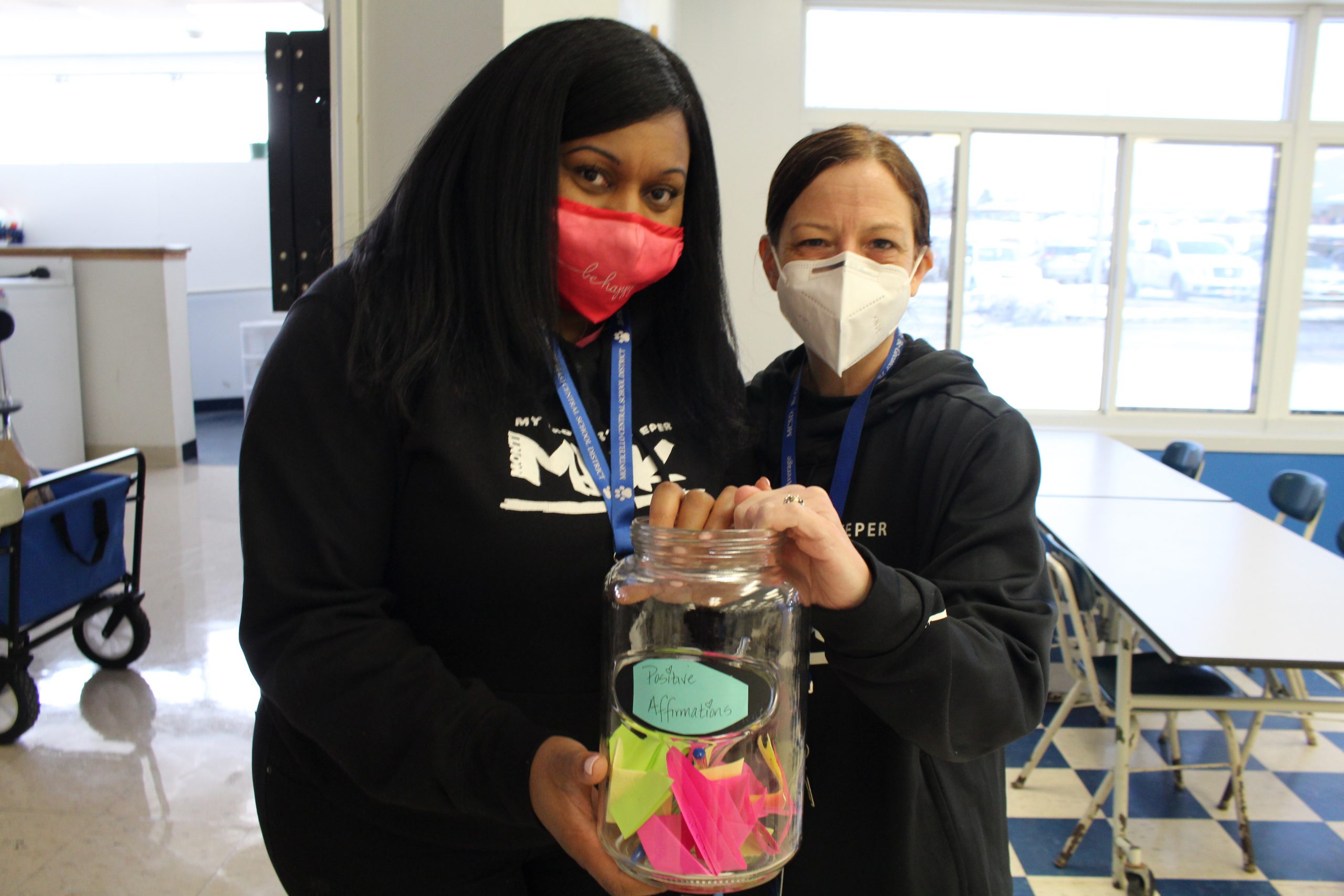 two staff members are holding up a jar that says "positive affirmations"