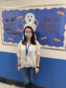 a female school counselor is posing in front of a bulletin board 