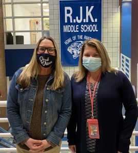 two female counselors are standing in front of  a RJK banner and smiling 