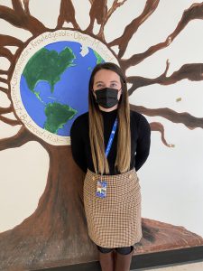 a female school counselor is smiling with a mural in the background