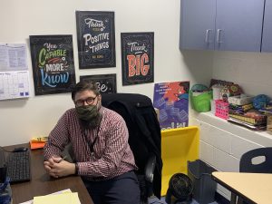 a male school counselor is seated at a desk 