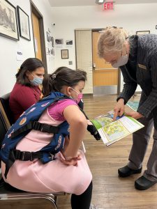 a teacher is showing a book to a seated student 