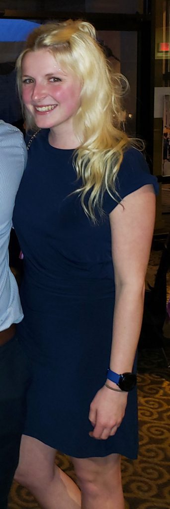 Amanda DePew wearing a dark blue dress smiling at the camera with her arm around someone.