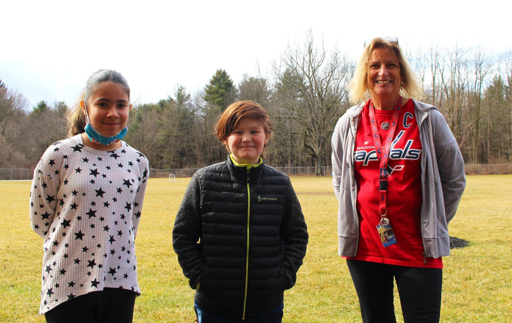 Two Emma Chase Elementary students with Maryann Swensen, the Social-Emotional Wellness Facilitator for Chase Elementary, standing outside with a forest as a background.