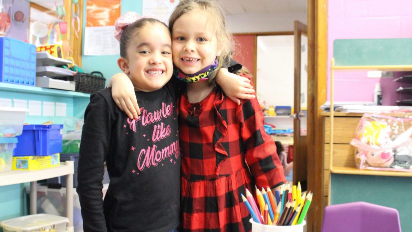 two kindergarten students are embracing and smiling