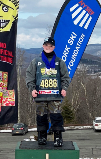 michael pappas is standing on a ski slope and smiling. 