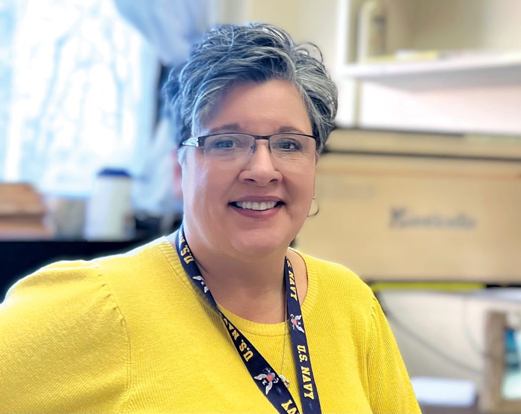 Christine Budinich is wearing a yellow sweater and smiling