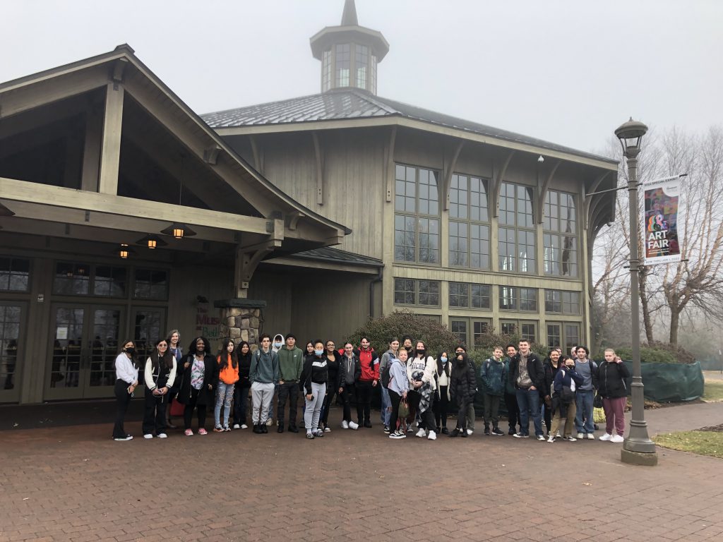 A group of students are posing outside of an art gallery