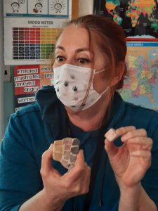 a woman is holding a piece of tile and showing it to the class