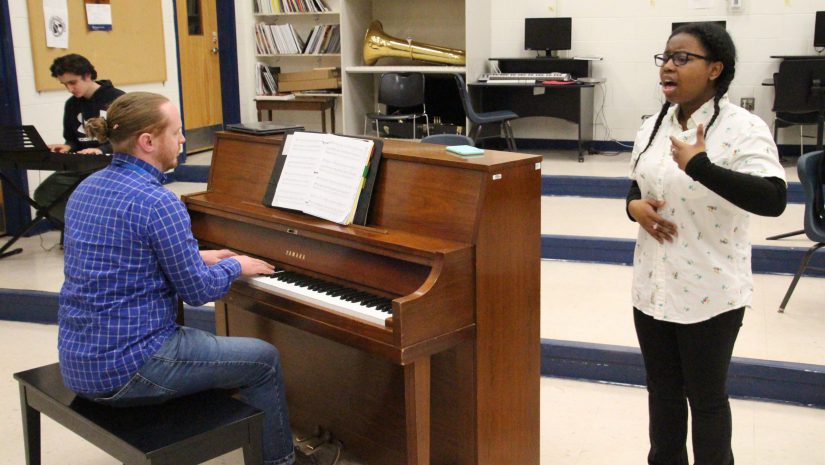 a teacher is playing piano as a student sings