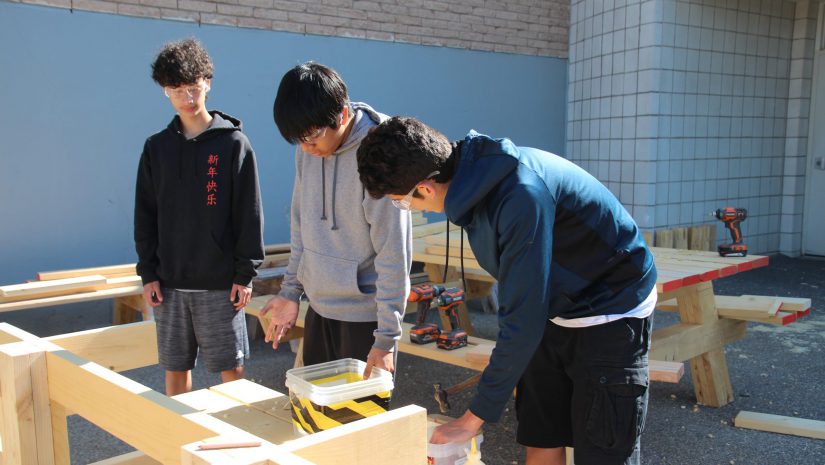 three students are working on a table