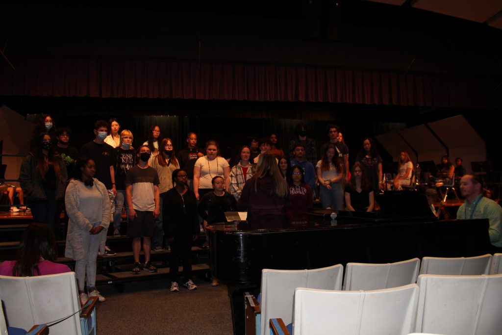 a student chorus is singing and standing on bleachers