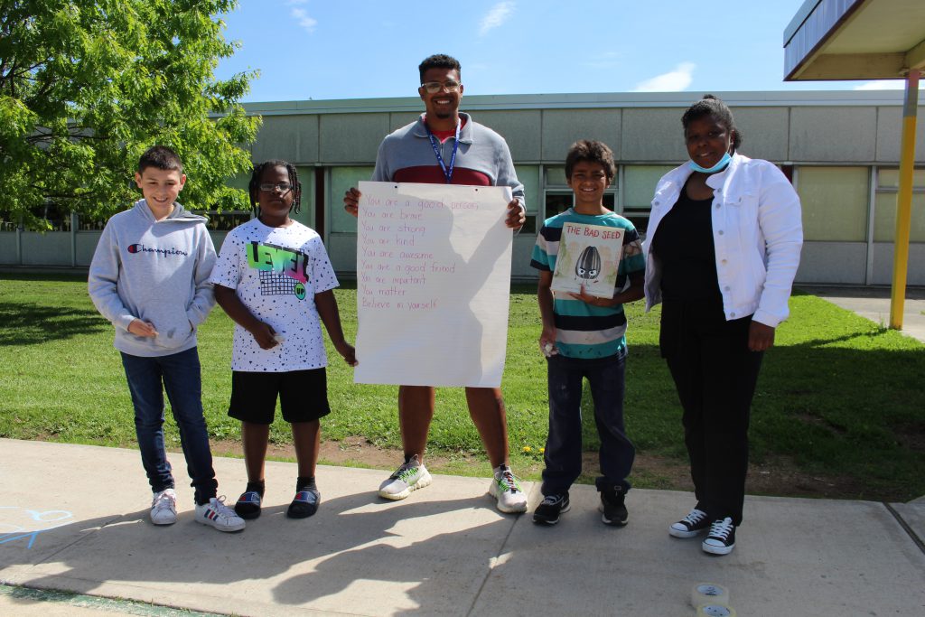 three students and two teachers are posing