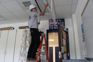 a construction worker is on top of a ladder replacing a light 