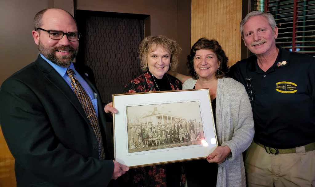 Gary & Judy Siegel stand with Superintendent Matt Evans and school board president Lori Orestano-James with the donated picture and all are smiling at the camera for a picture.