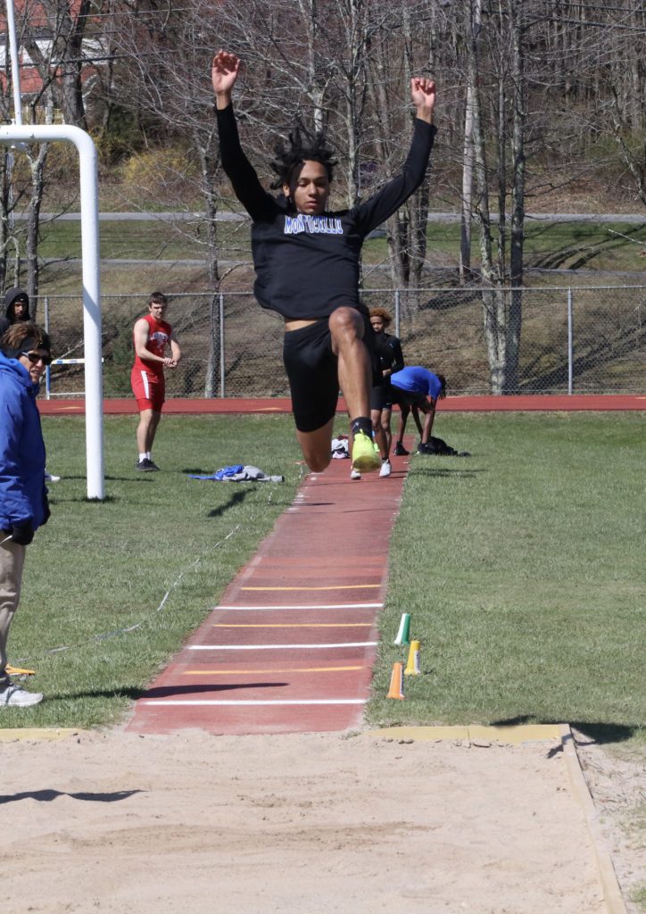 a male track athlete is jumping in the air