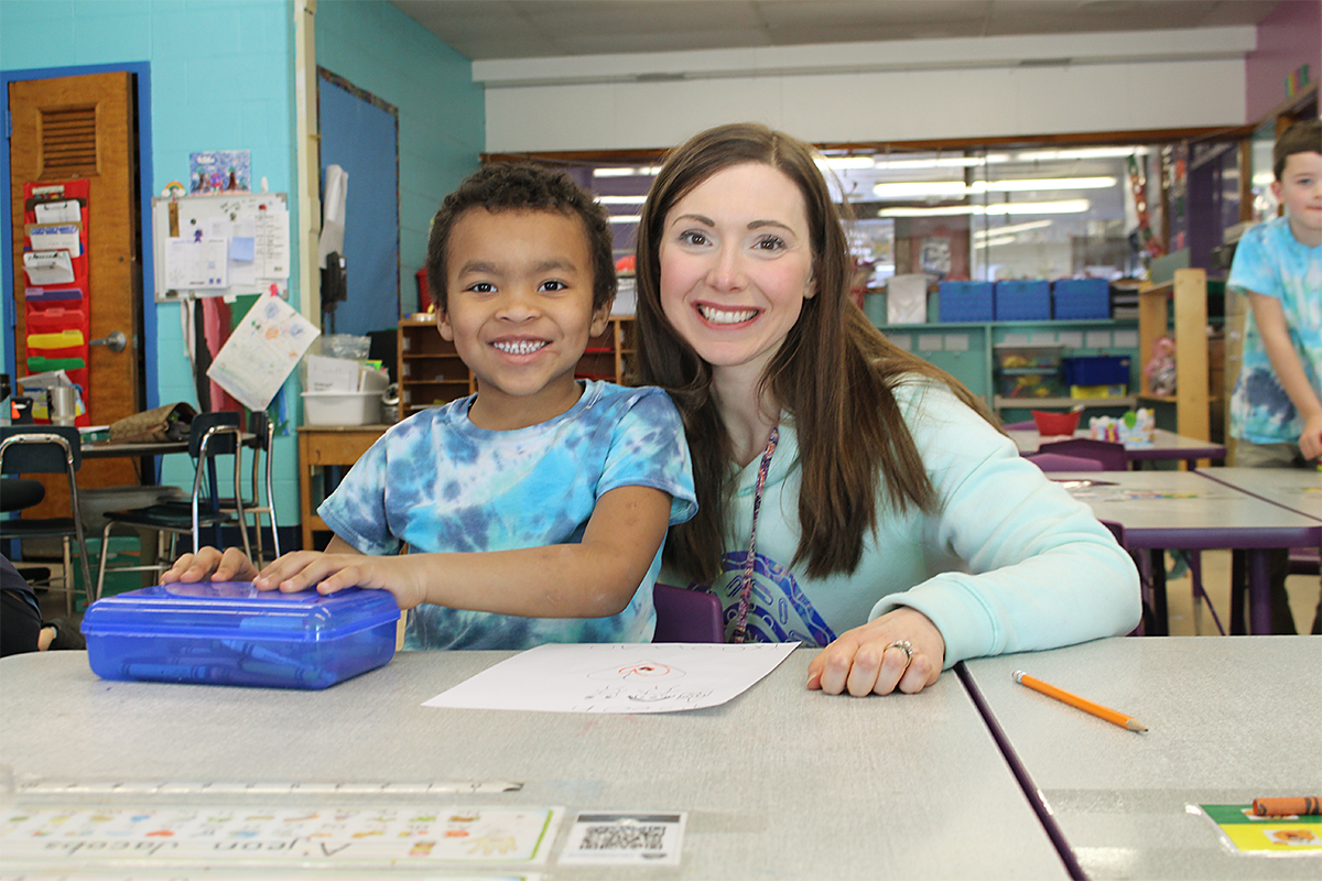 smiling teacher and elementary student in classroom