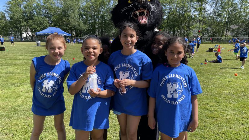 a group of young female students wearing blue Cooke ELementary shirts are posing with a Panther mascot
