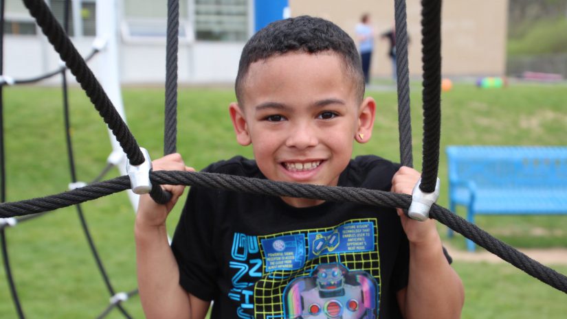 a young boy is playing on a playground and smiling at the camera