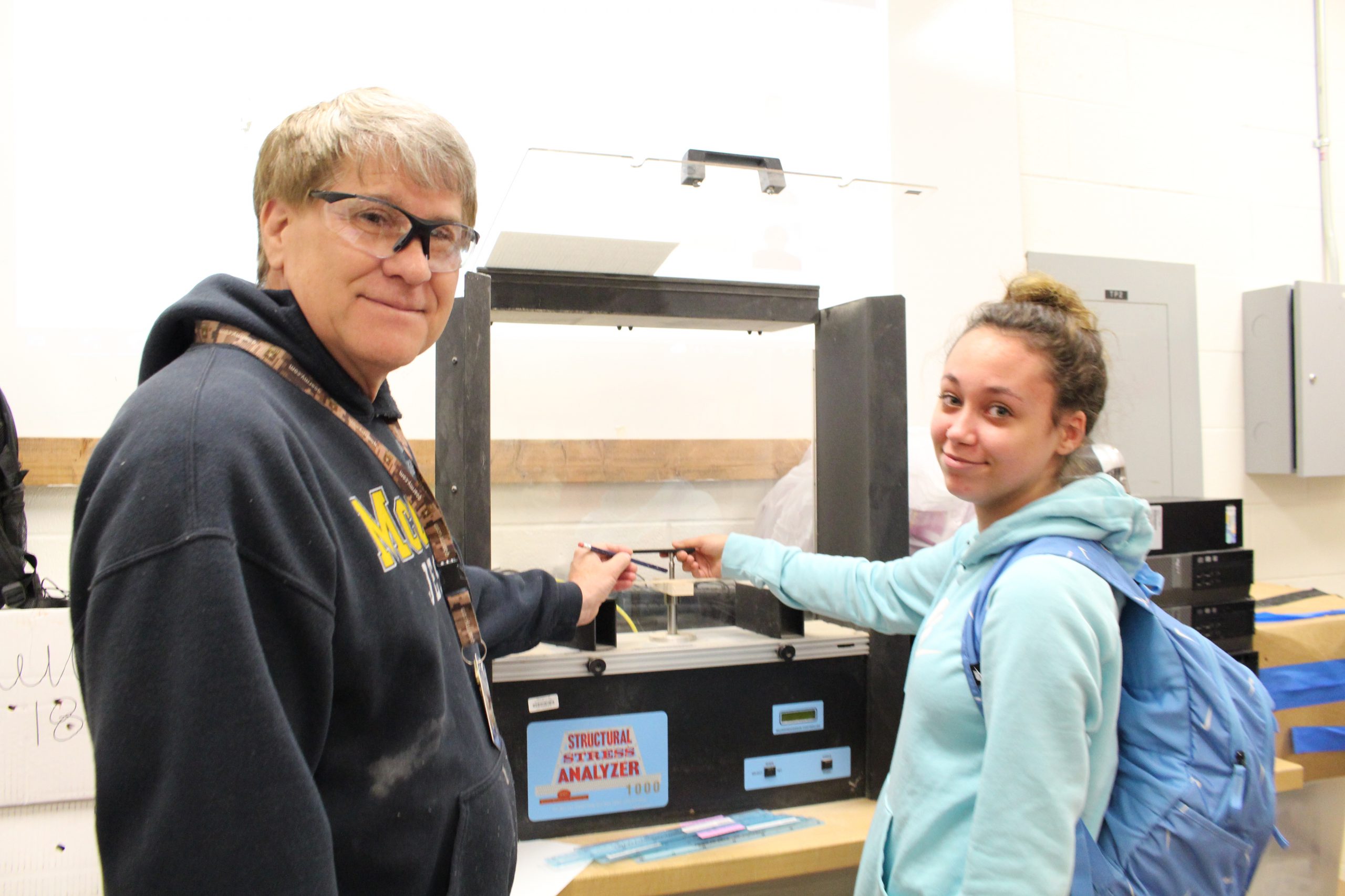 A teacher is showing a student a technique in woodshop.