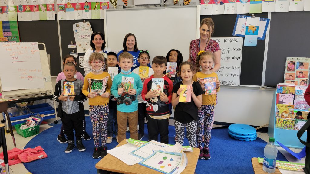 a group of students are holding up books and smiling