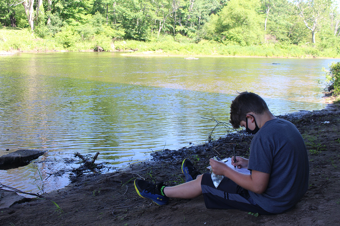 student working on project outdoors next to body of water