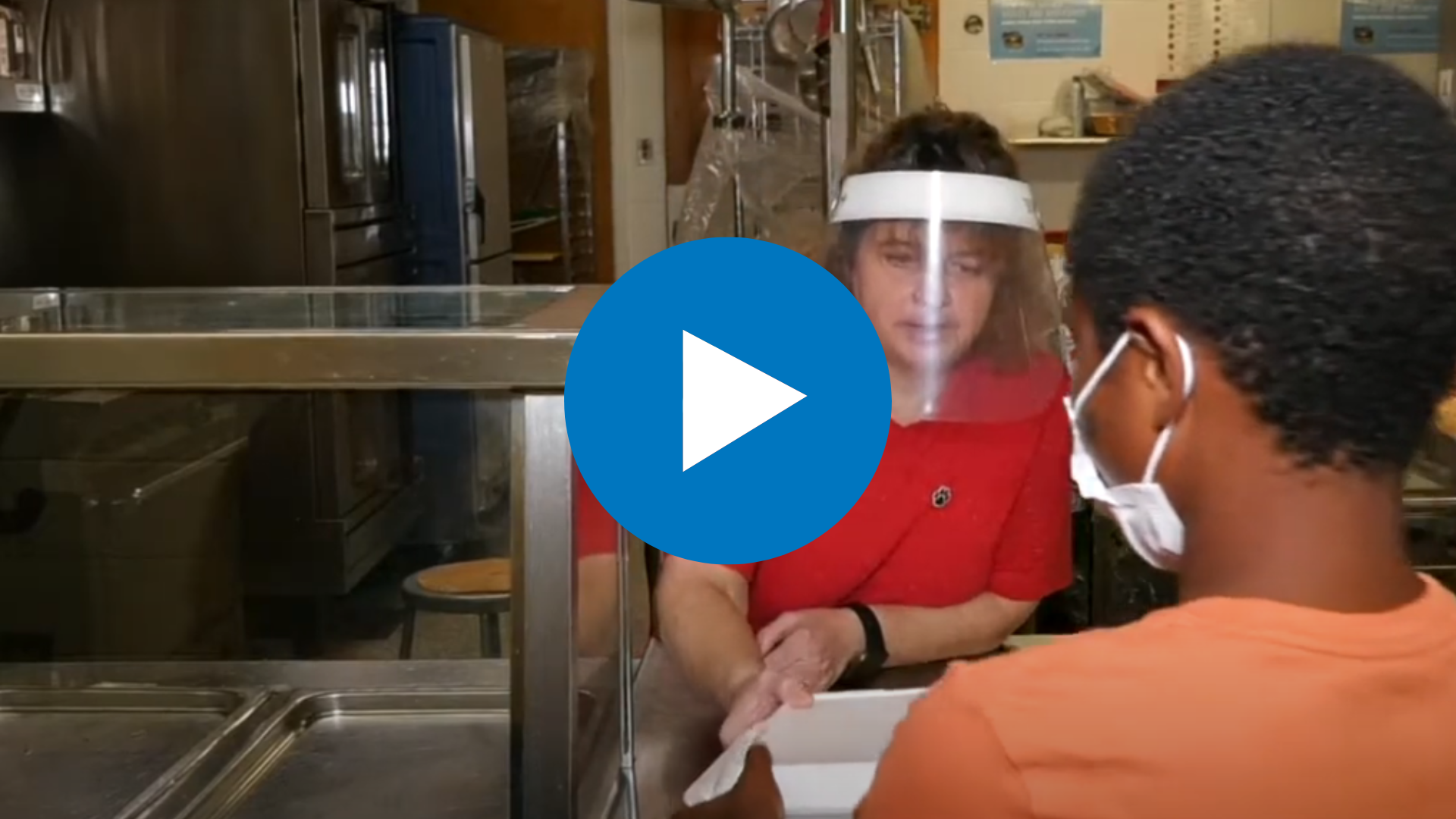 a food service worker is handing a tray to a student 