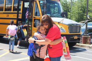 a teacher is embracing a student in front of a bus