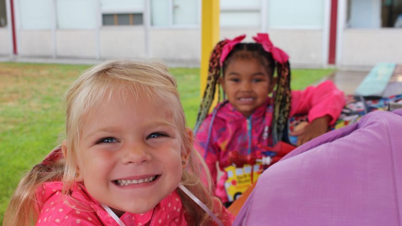 two girls are smiling at a table