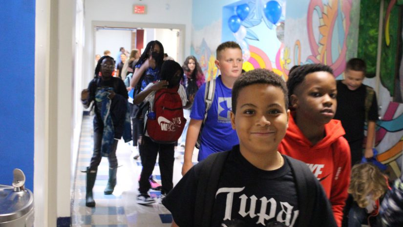 students are walking down a hallway during the first day of classes