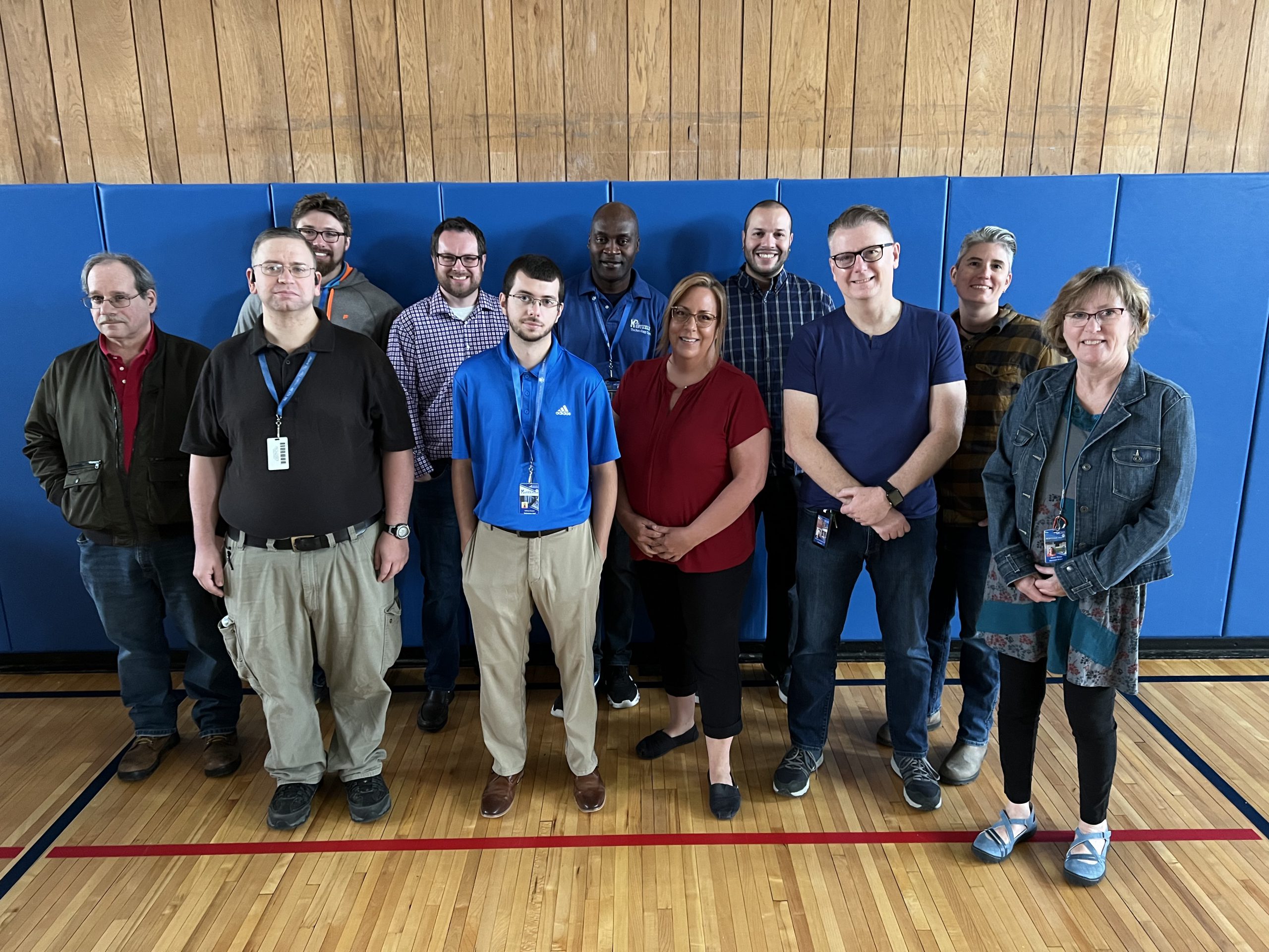 a group of men and women are posing in a gymnasium