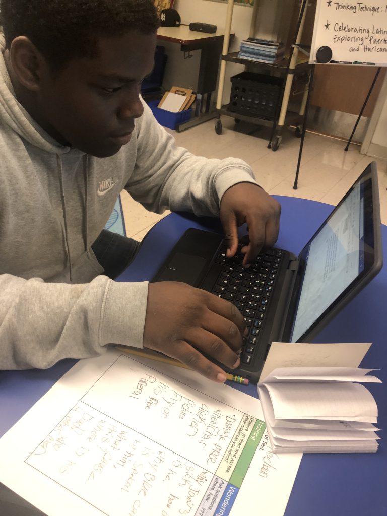 a teen boy is seated at a desk working on a homework assignment 