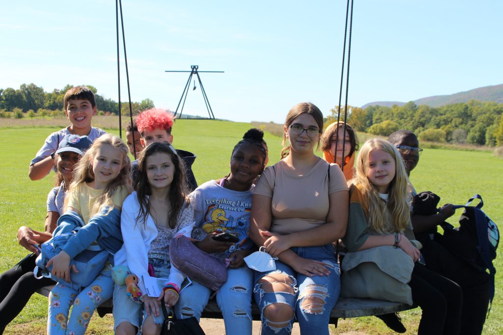 a group of students are seated on a sculpture 