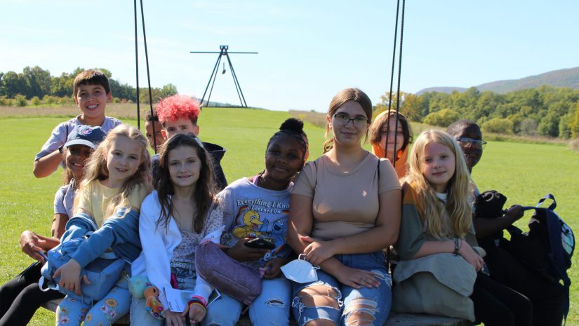 a group of students are seated on a sculpture