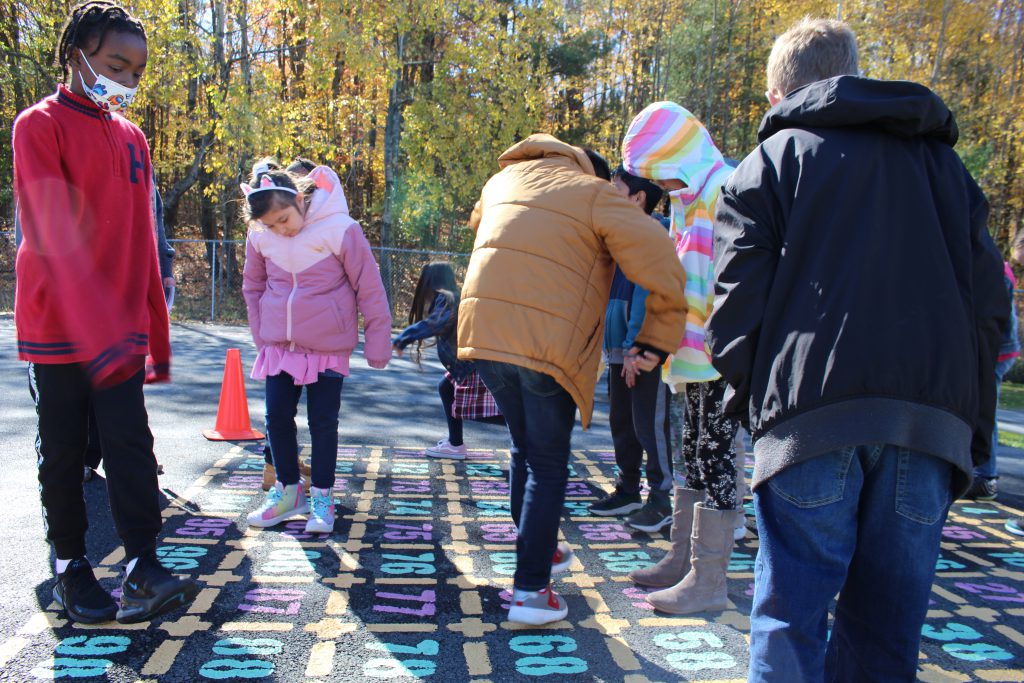 students are standing on top of the numbers chart. 