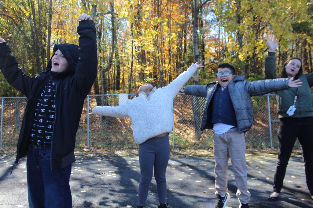 three students have their hands extended to the sky. They are in the middle of a cheer. 