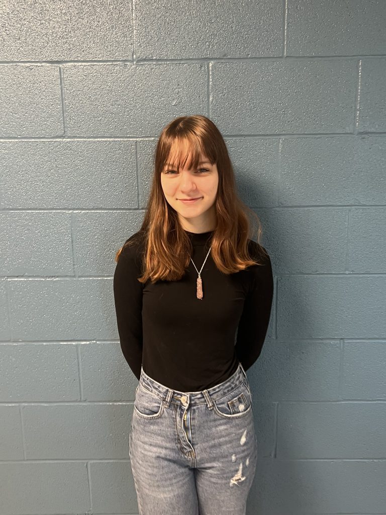 Leanna Auletta is posing in front of a wall 