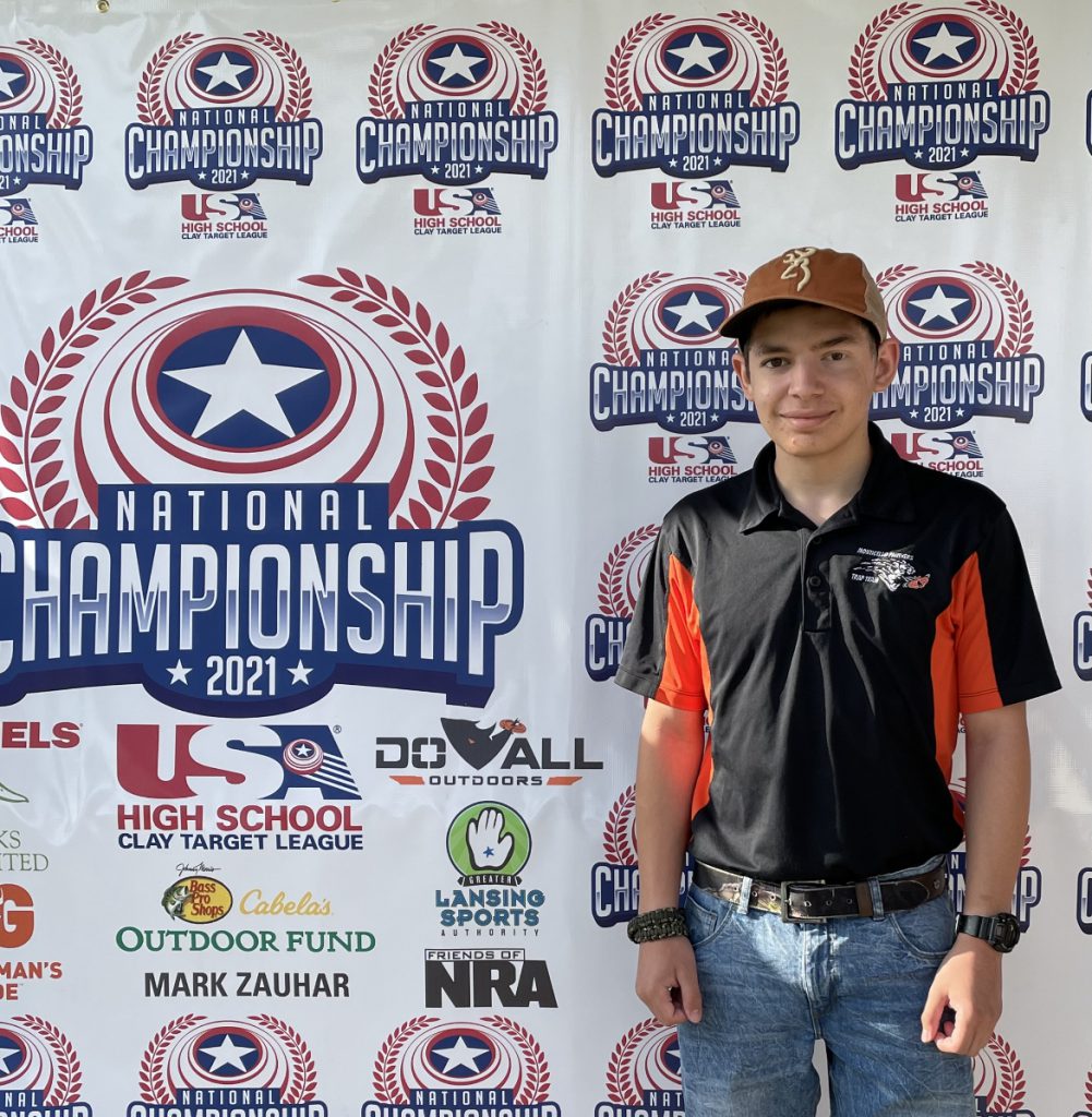 Michael Feltman is posing in front of a banner 