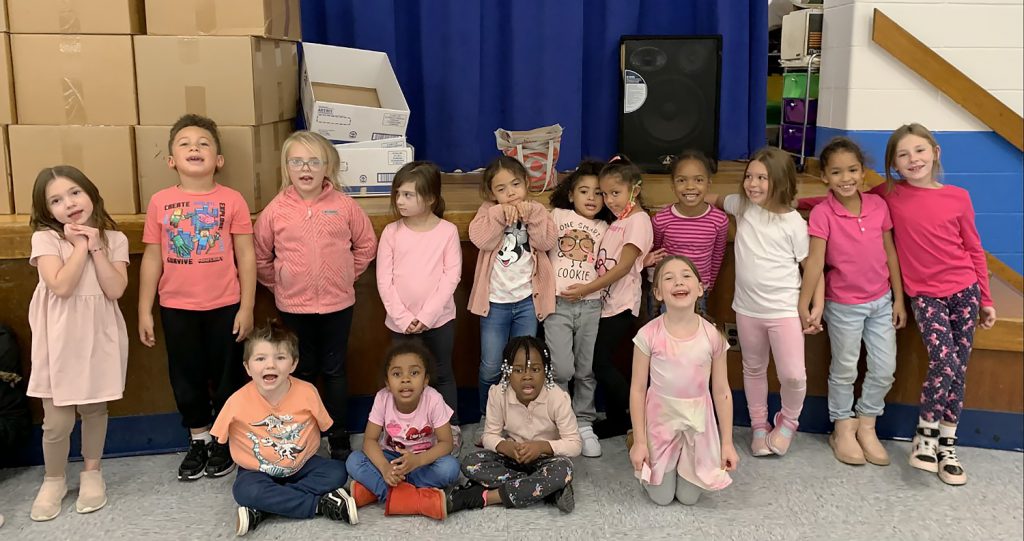 Students wearing pink and denim and smiling for a group photo.