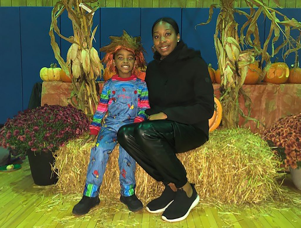 A mother and son smiling for a photo on a bale of hay.