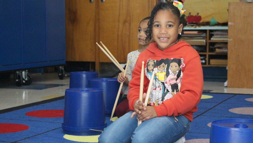 a student is holding drumsticks and smiling