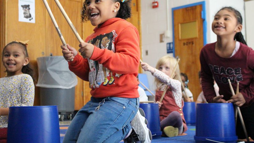 students are holding drumsticks and drumming