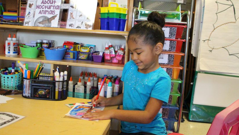 a young girl is seated and working on a project