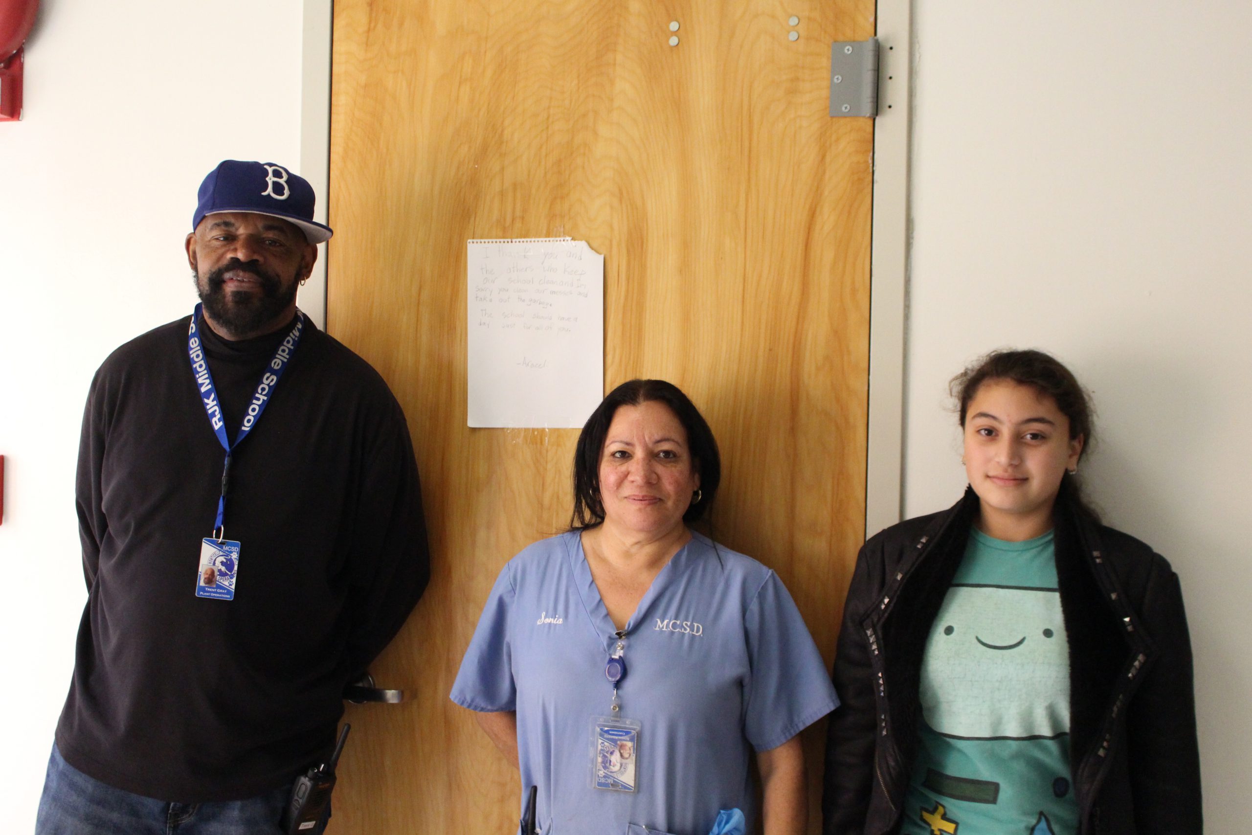 a female student is posing with two custodians and smiling.