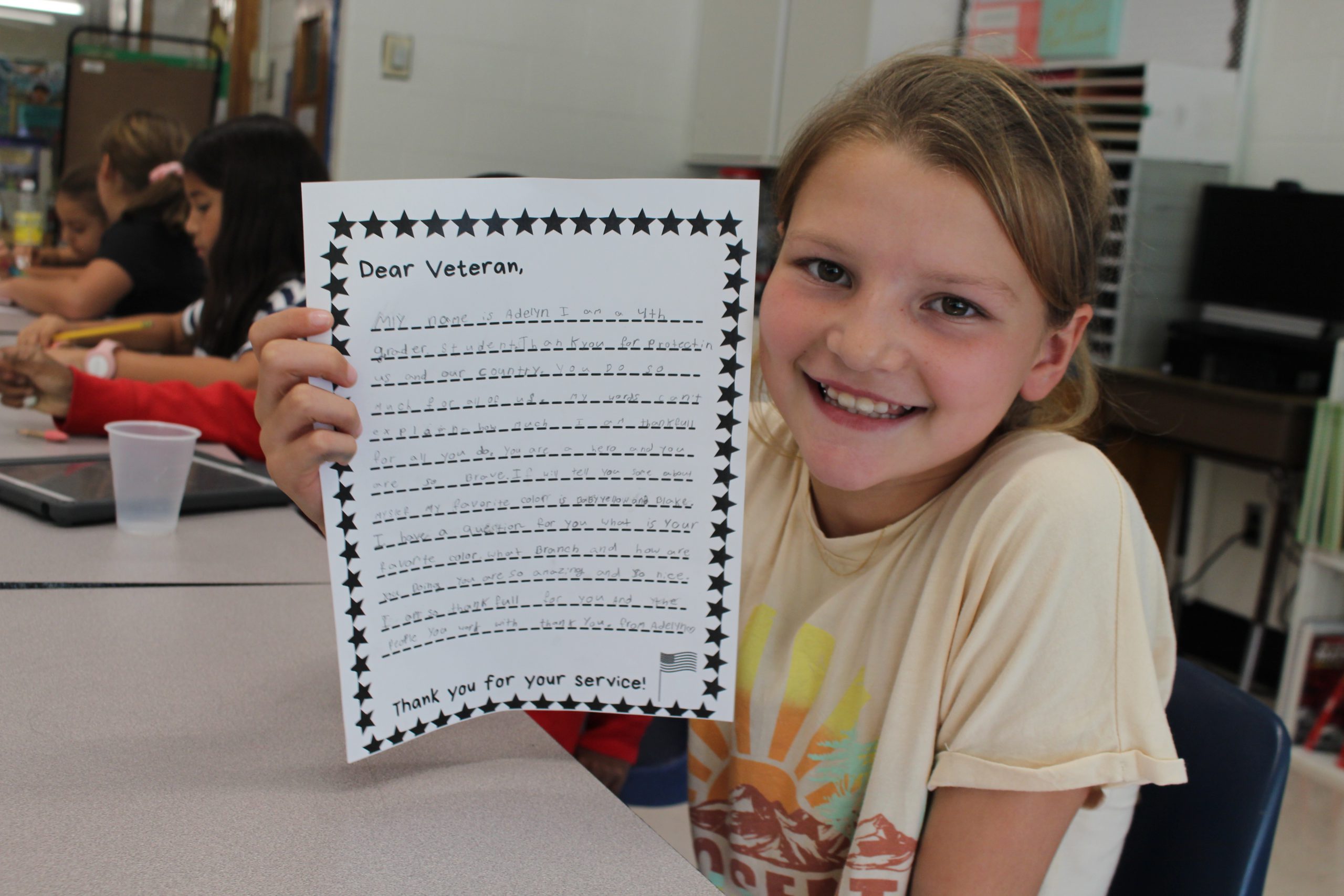 a student holds up a letter that she wrote to a veteran