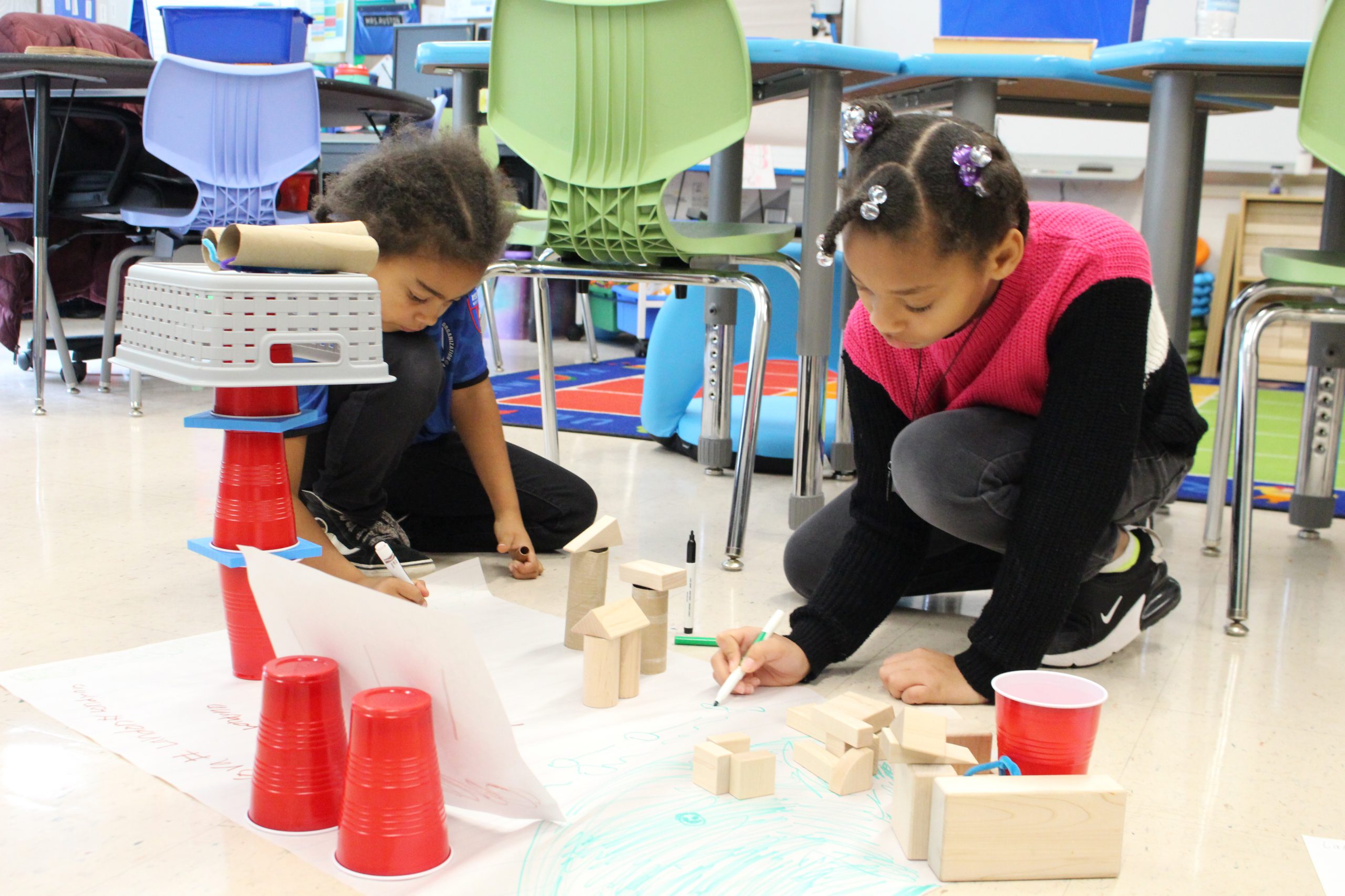 two students are working on a project. They are writing on a piece of paper. 