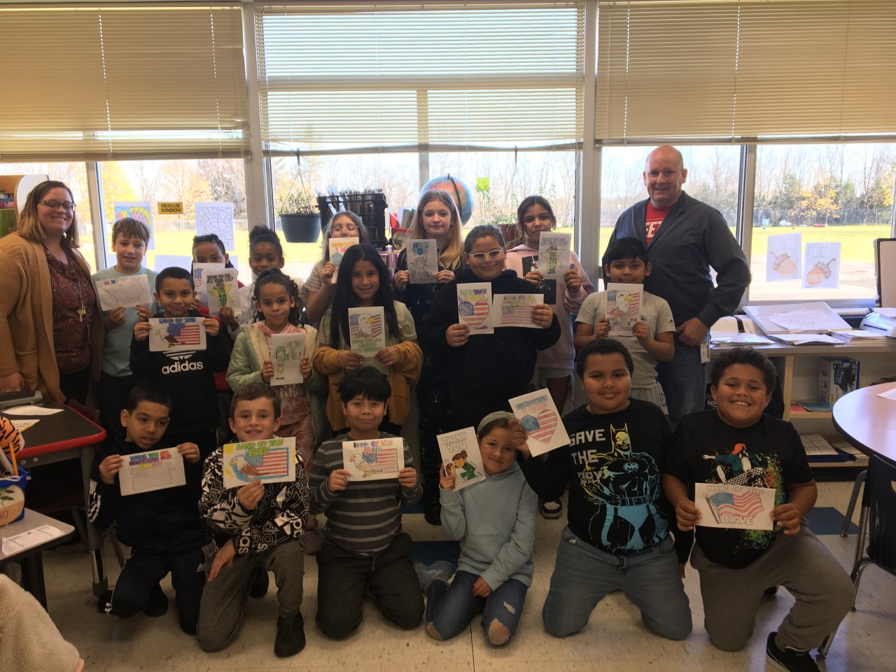 a class full of students are holding up letters that they wrote to veterans