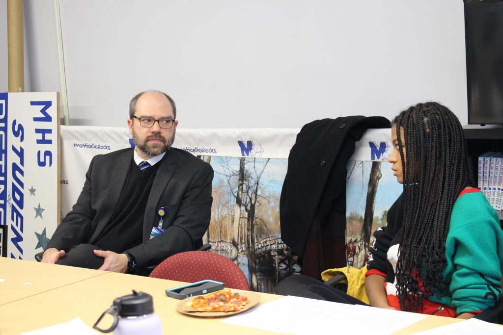 Dr Evans is seated at a table in conversation with a student 