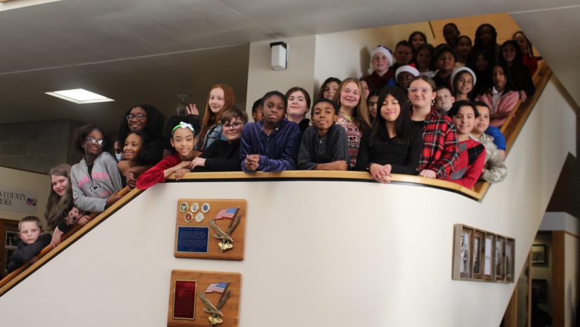 a group of middle school students are posing on a staircase