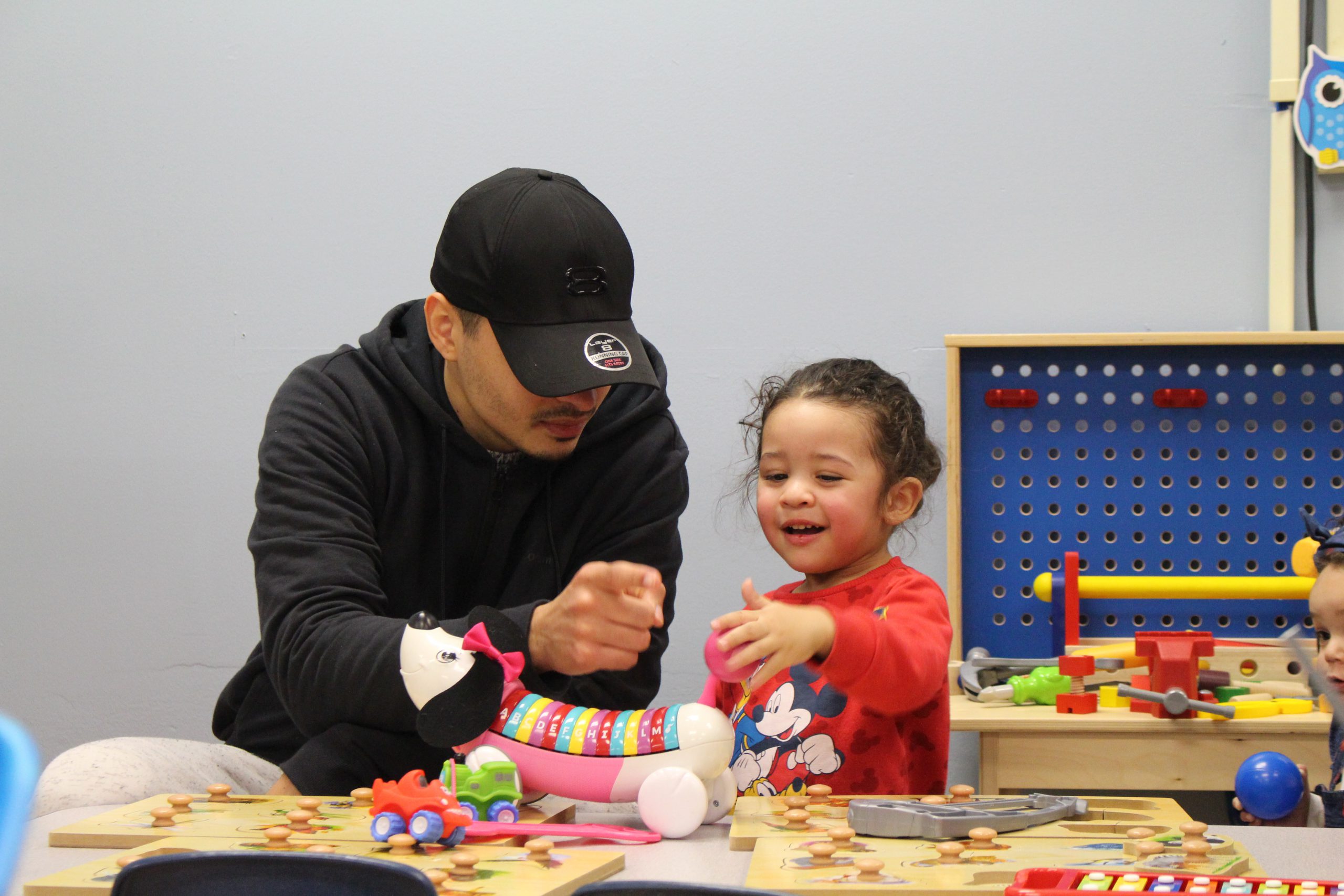 a father and child are seated at a table and playing with toys 